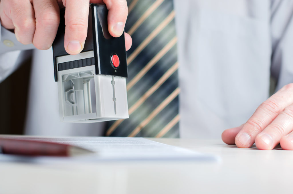 a stamp in a man's hand notarizing document